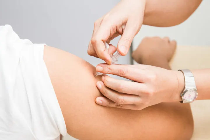 A practitioner giving an injection in the upper arm