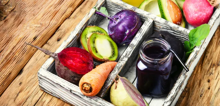 A crate of fresh vegetables, fruit and juice