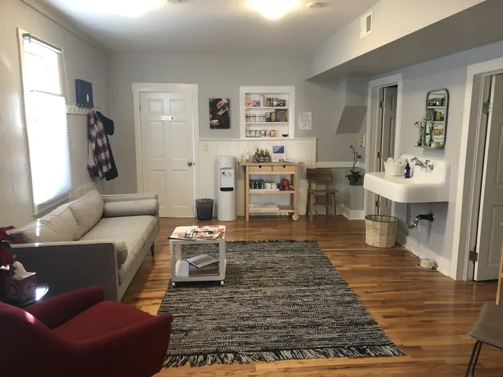 The bright waiting room with a sofa and wood floors